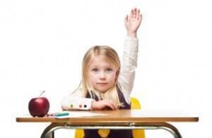 Child sitting at a desk raising their hand