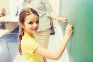 student writing on chalkboard