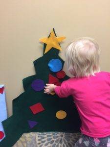 young student putting felt ornaments on felt Christmas Tree