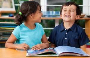 Two kides reading a book at a table