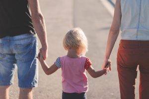child holding hands of two adults