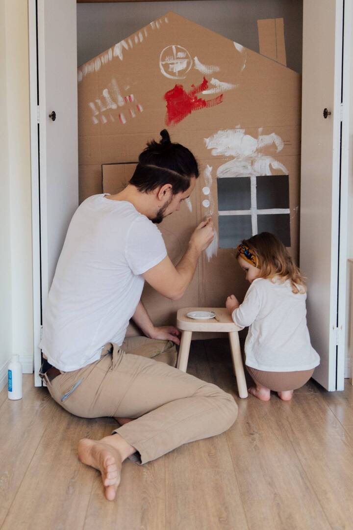 Child and parent building a cardboard house
