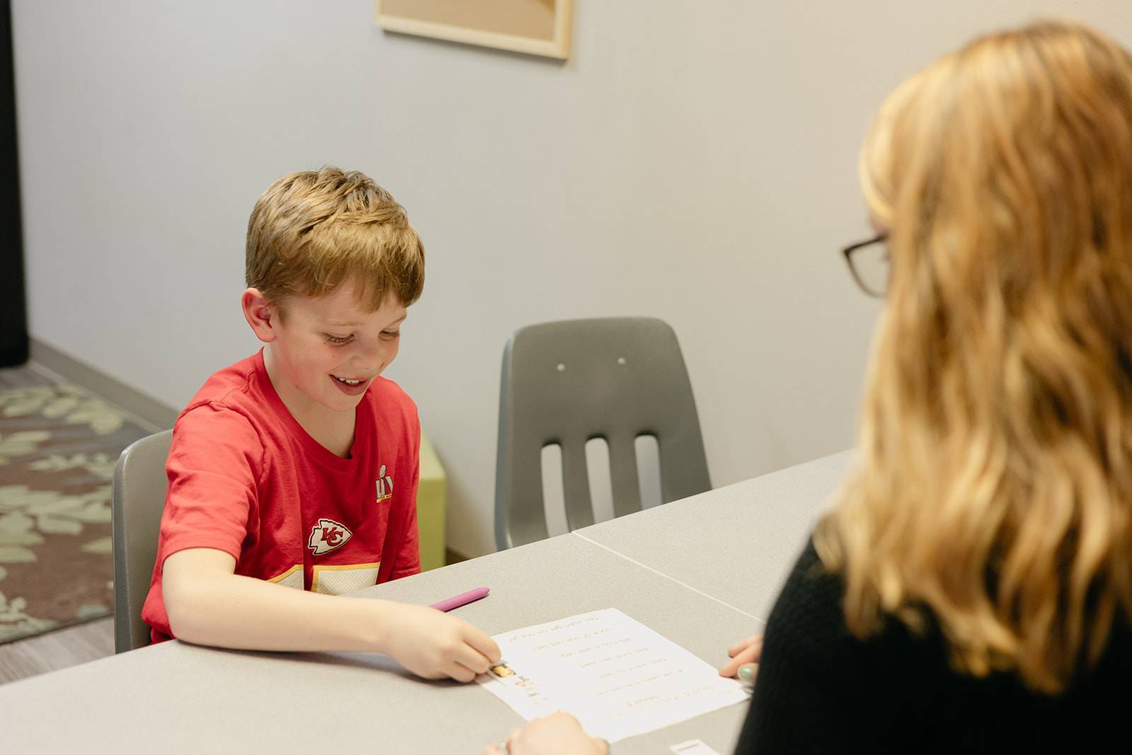 young boy reading book with speech language pathologist