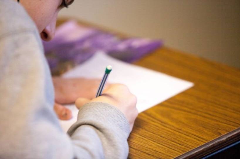 Student writing on paper at a desk