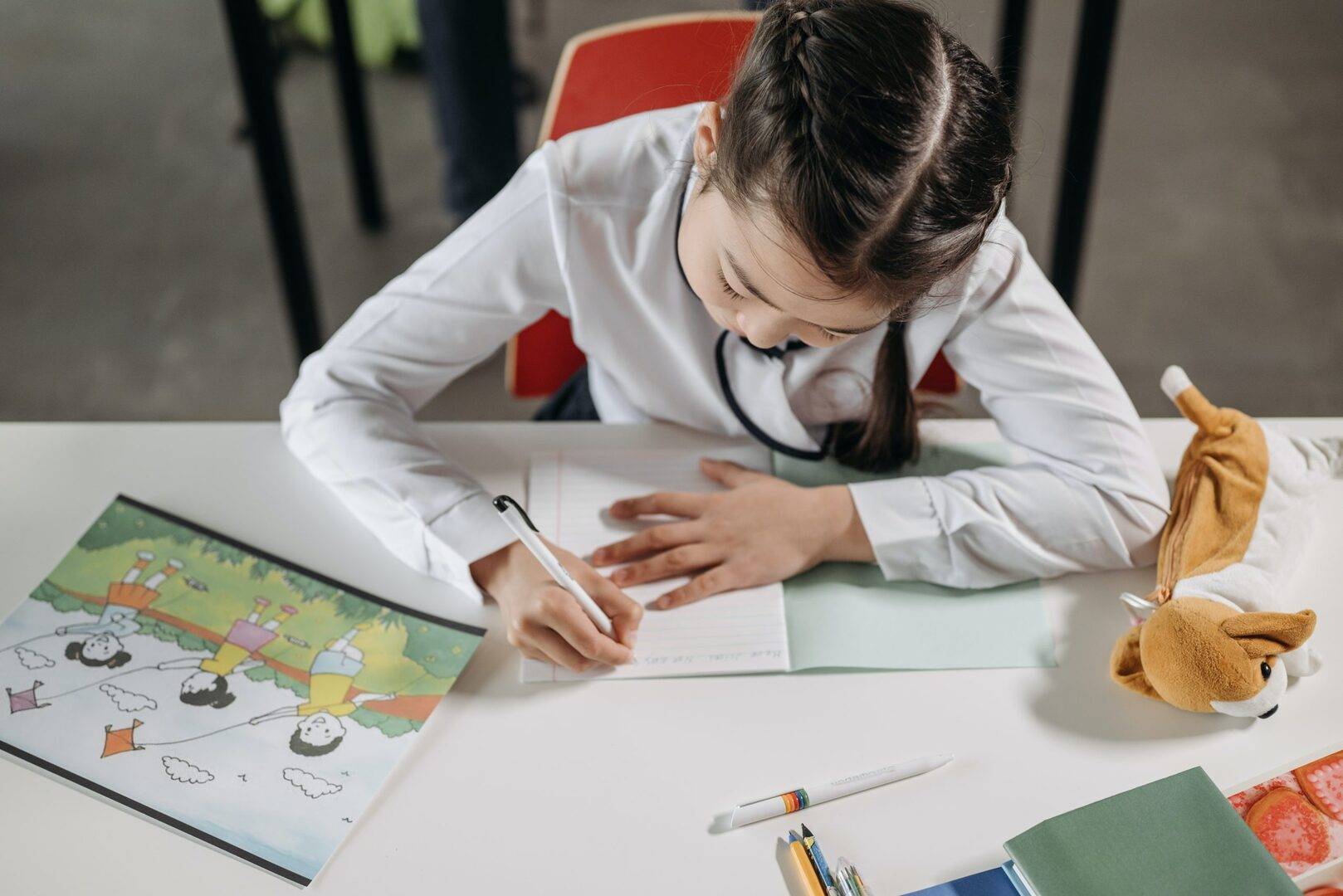 Girl sitting at a table writing in notebook