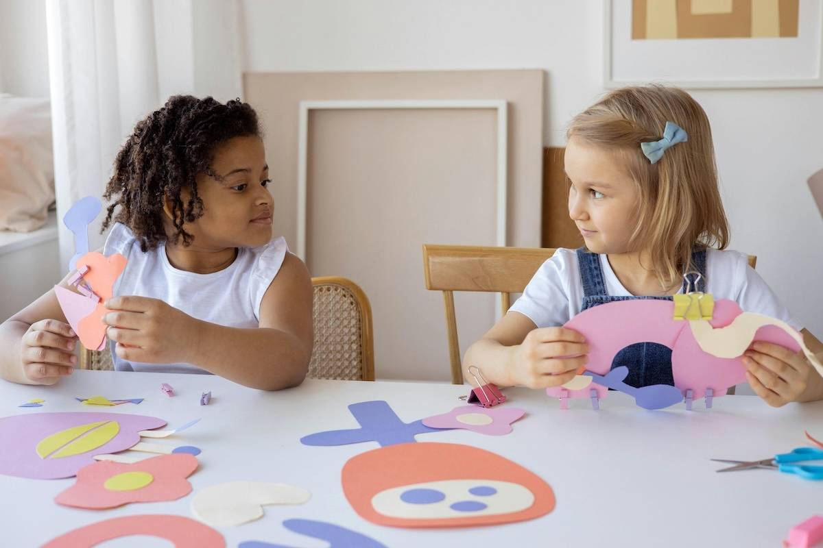 2 young girls crafting with construction paper.