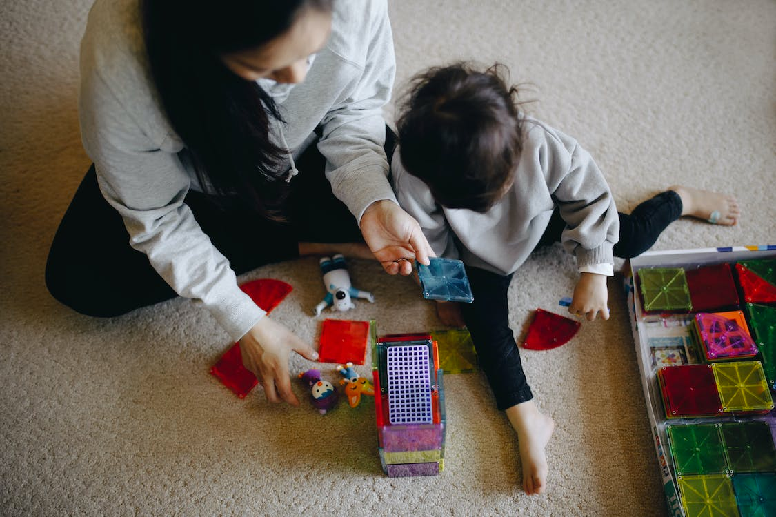 mother and child playing with toys on the floor.
