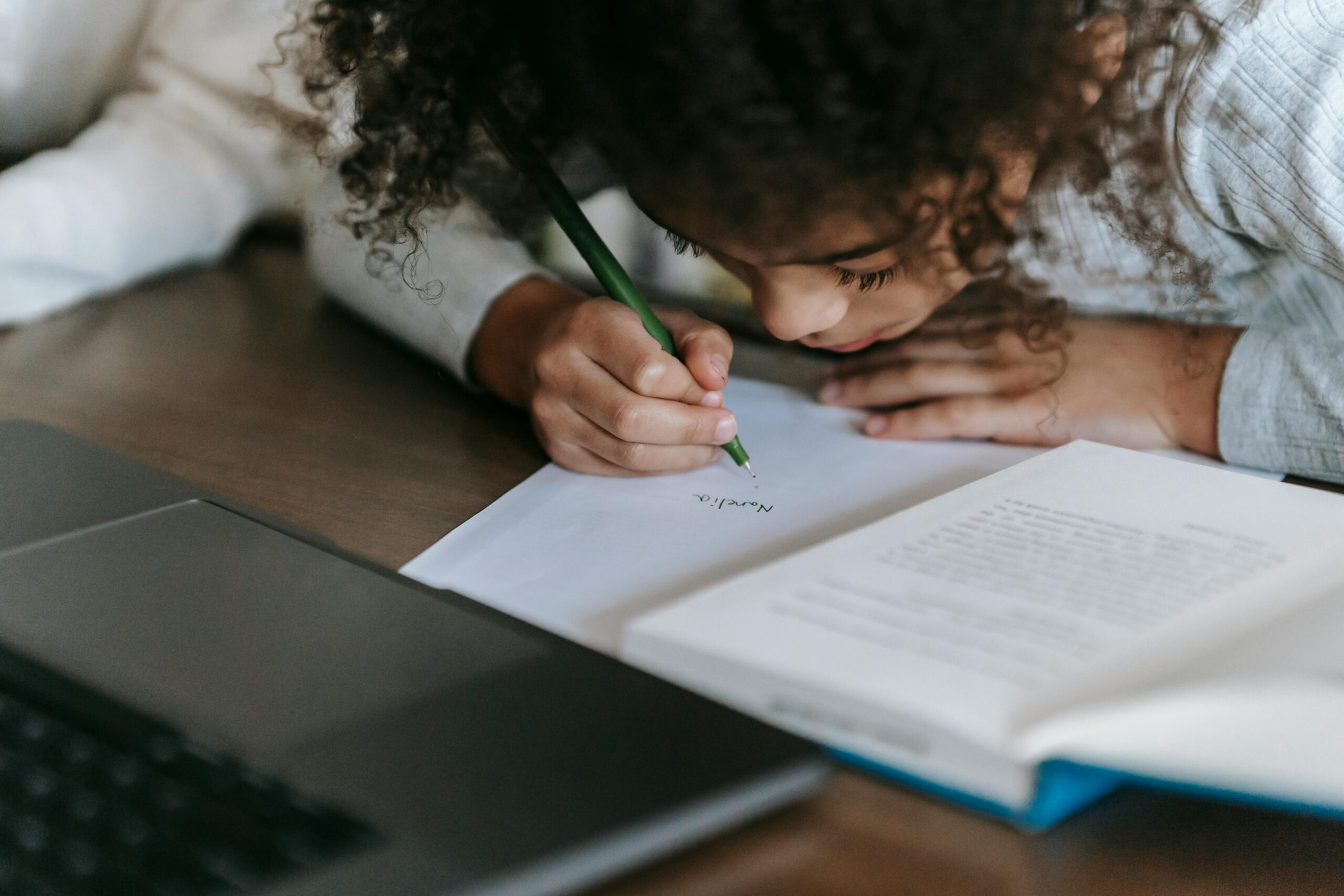 child uses a pen to follow the lines of a book