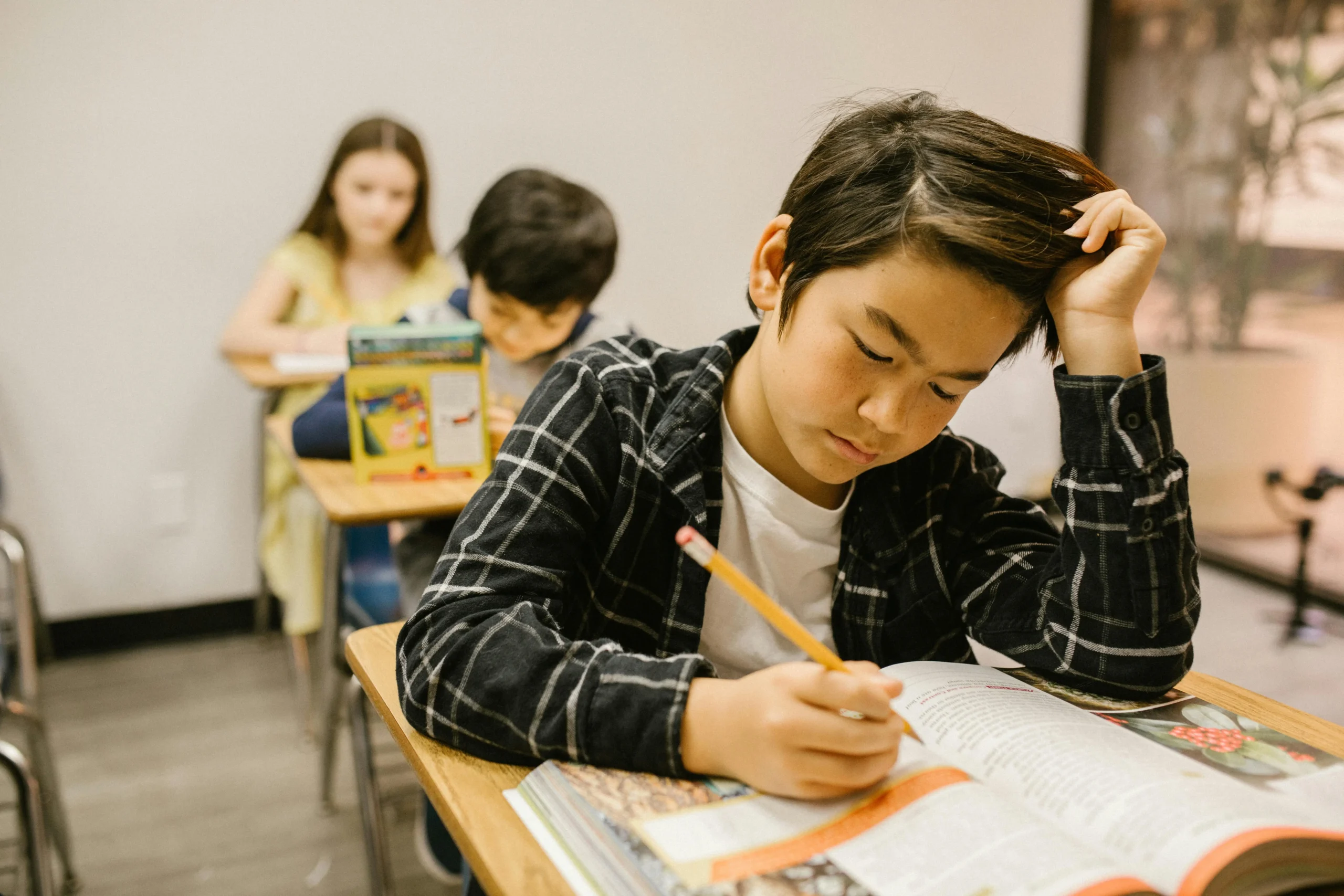 child sits at desk working in school with head in his hand