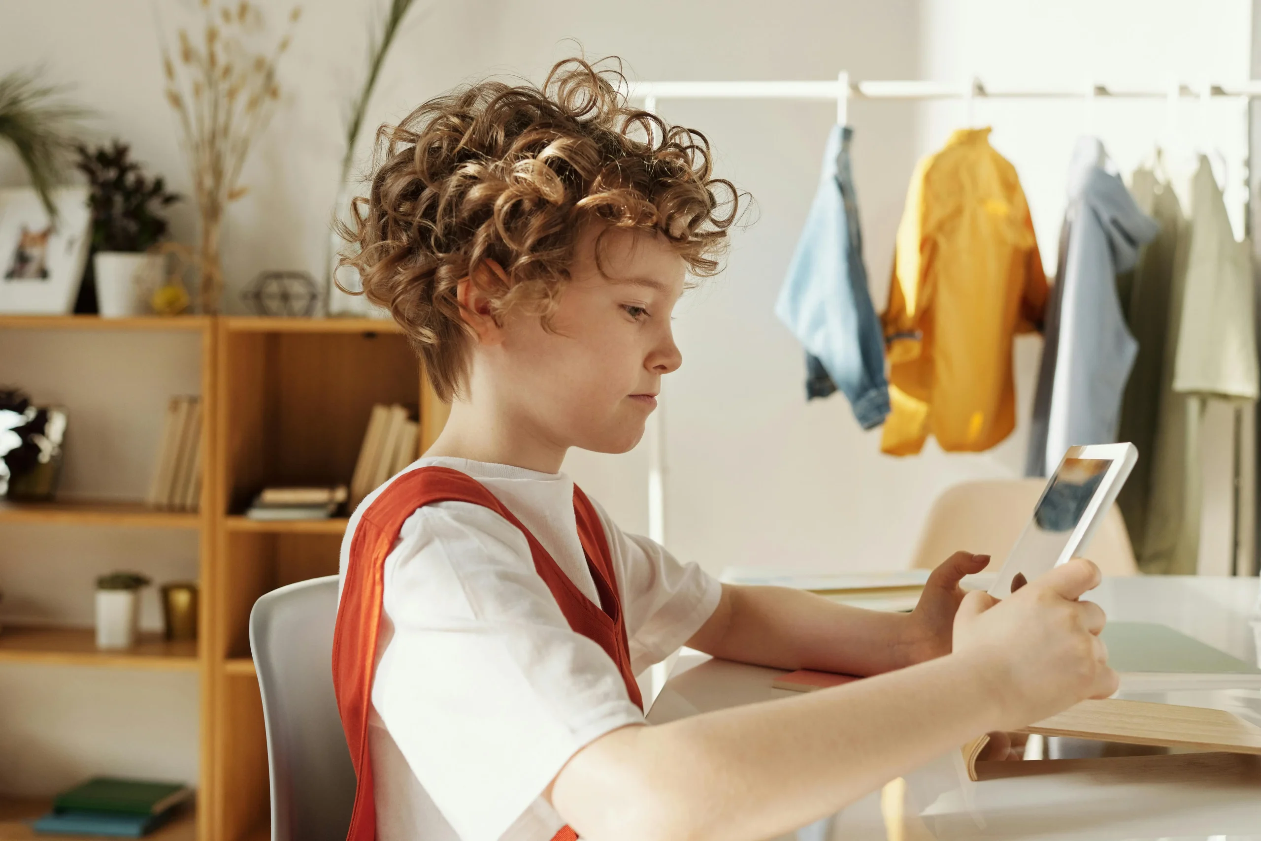 child sits at a desk looking at a tablet