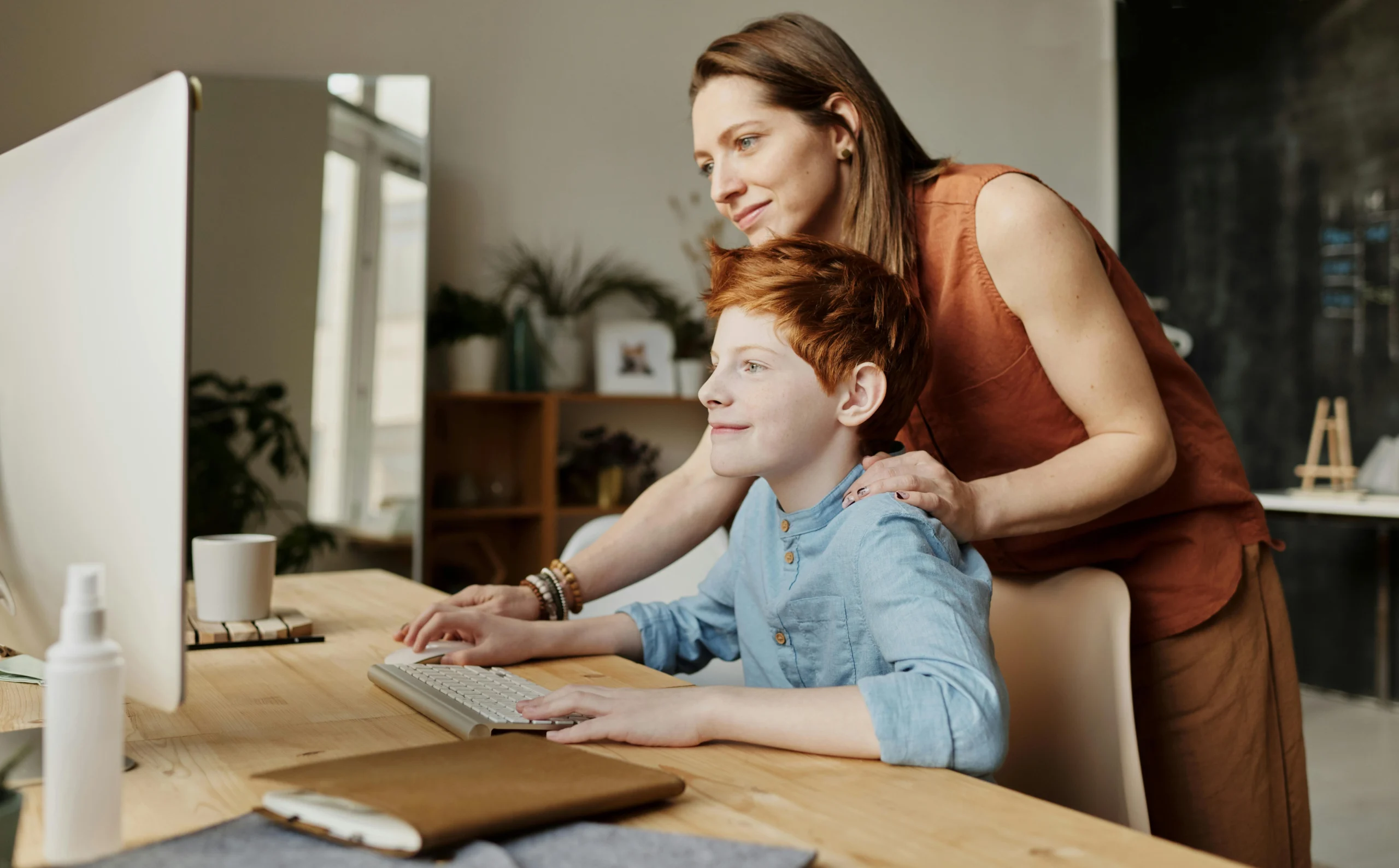 Woman with child at computer Woman stands over school-aged child at computer, helping him
