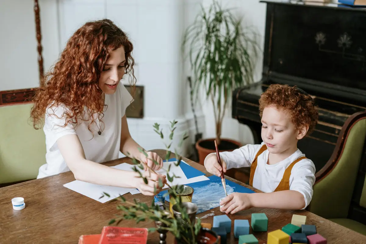 mother and son sit at table doing a craft