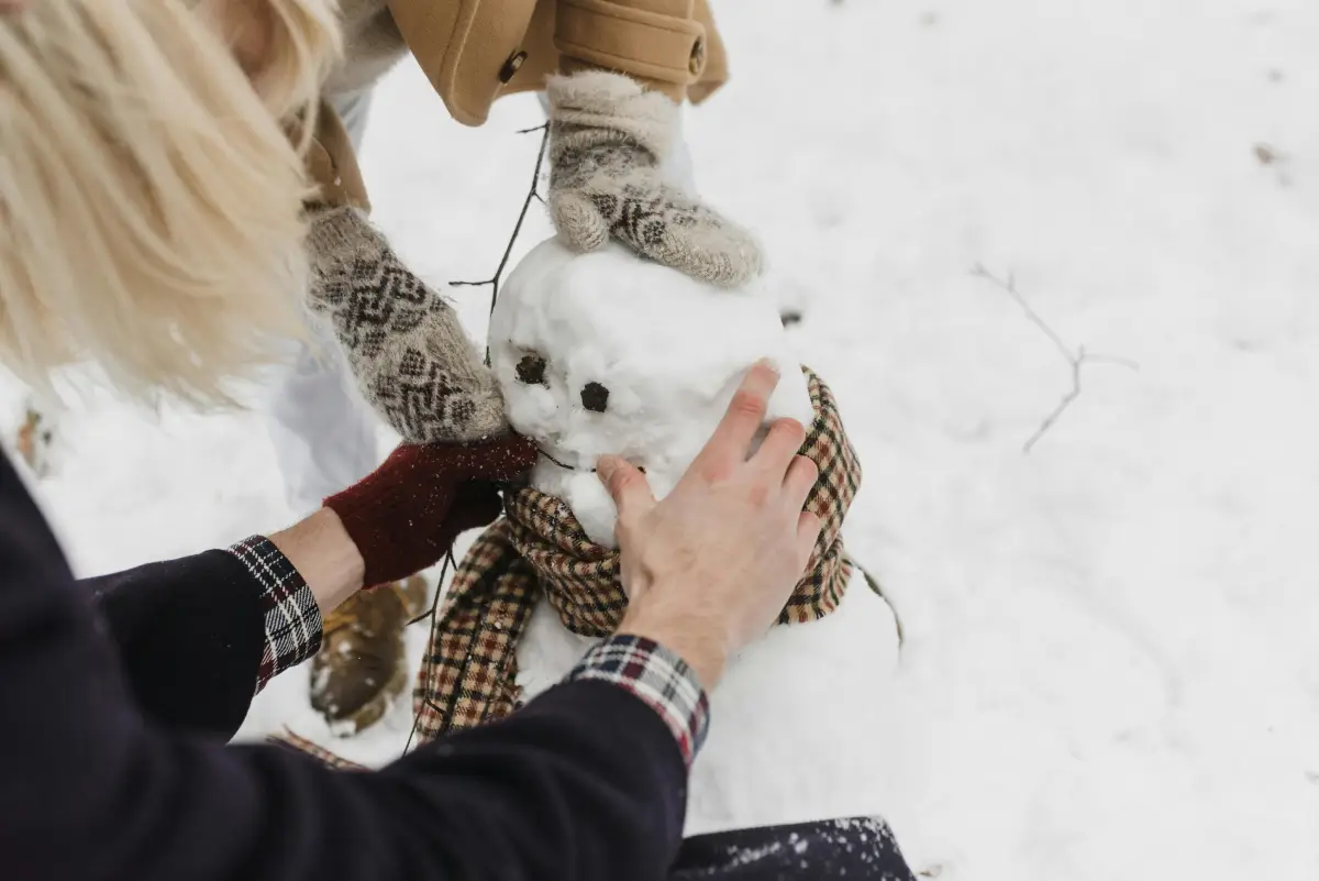 a woman and child build a snowman together
