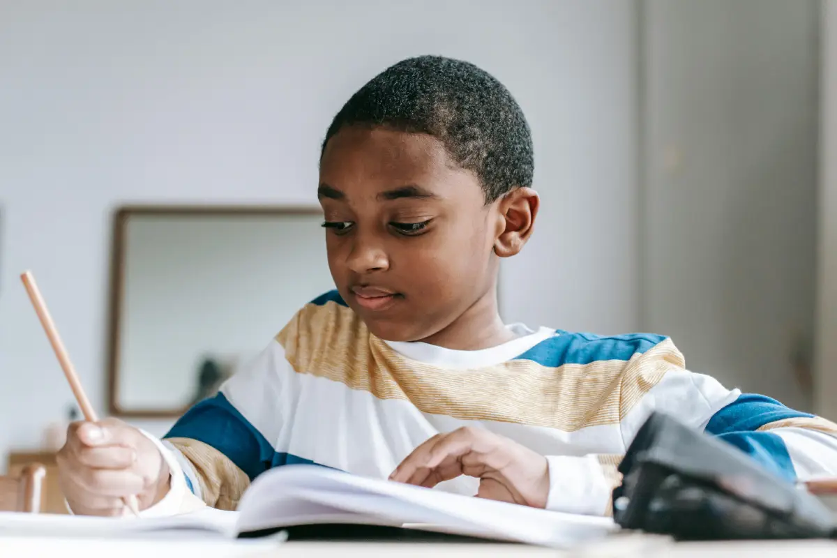 boy writes school-ages boy writes in a notebook at a table