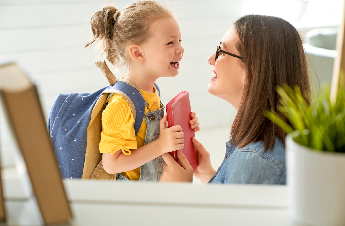 Mom hands kindergarten-aged daughter a notebook before school