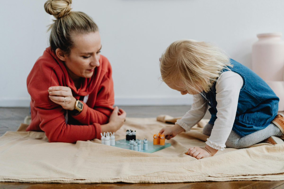 mom daughter play mother lays on floor as toddler plays with blocks