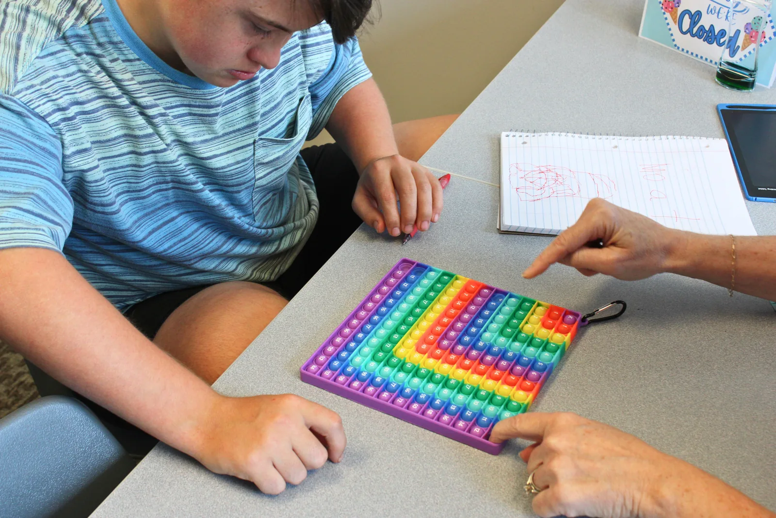 fun-ways-to-build-math-skills-at-home Child and therapist using a colorful hundreds grid to practice math skills at ETLC