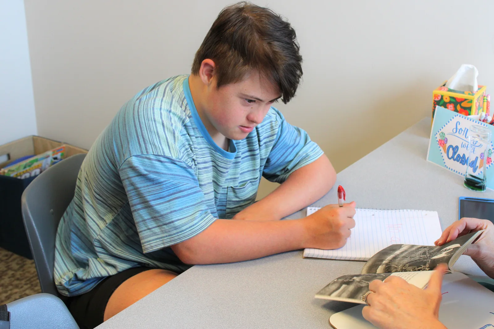 how-to-help-your-child-tell-better-stories Student writing a story in a notebook during a narrative language session at ETLC