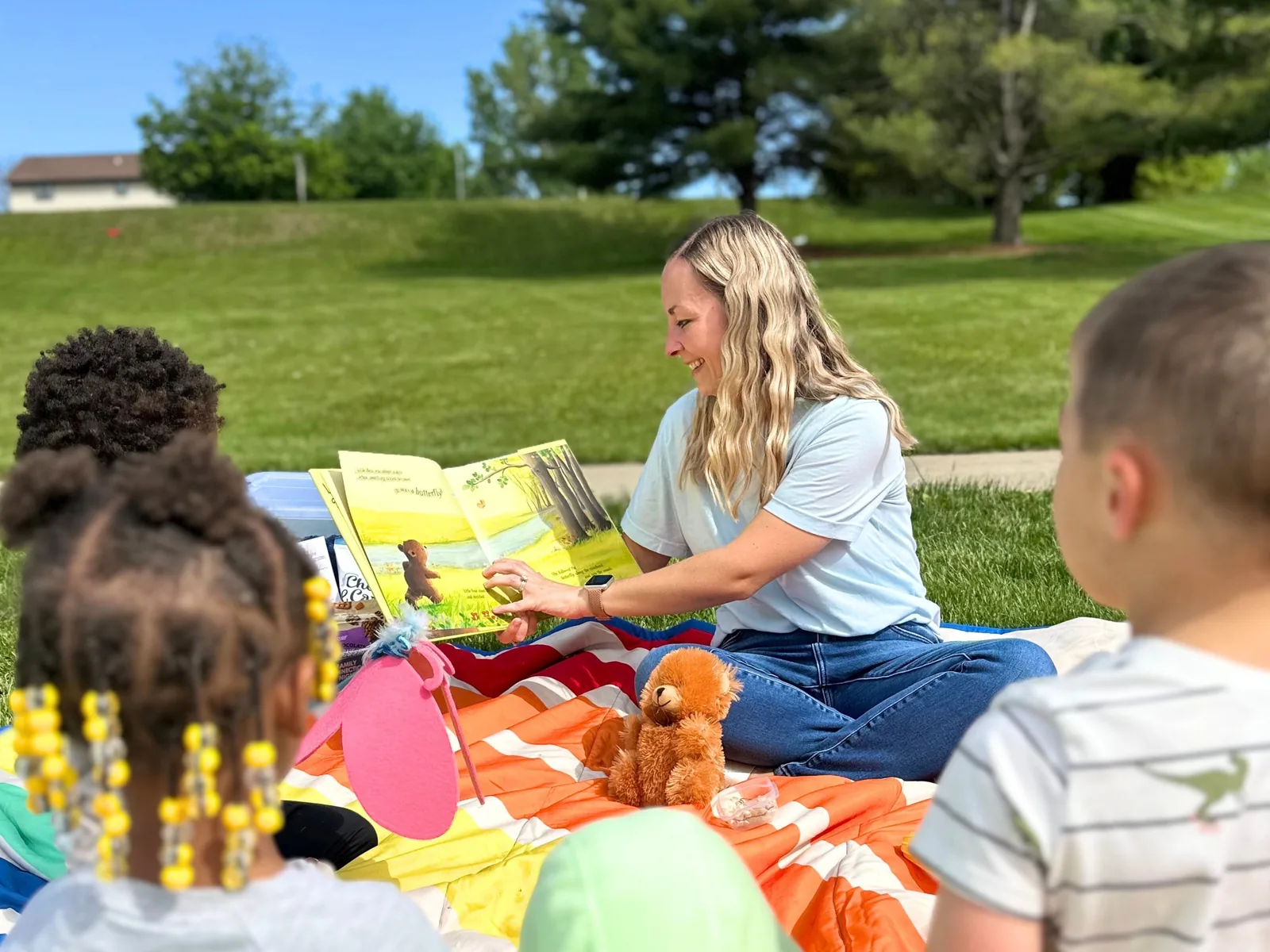 ETLC therapist reading books with children outdoors on a blanket during a summer session