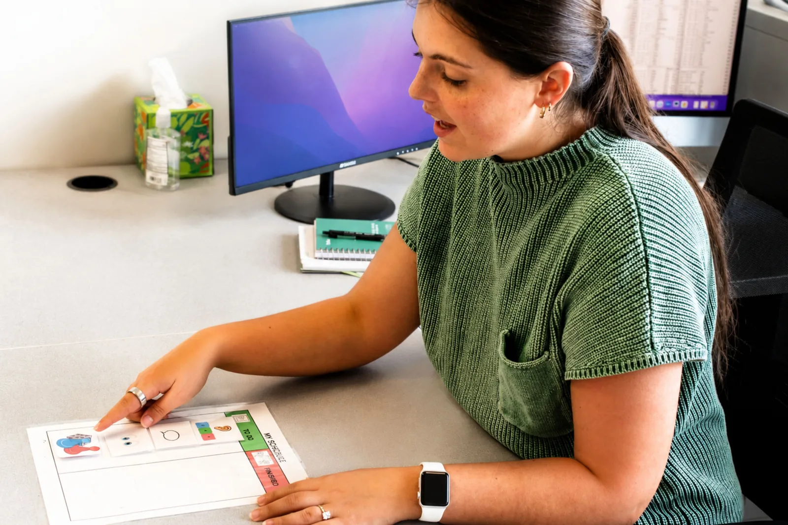 how-visual-supports-and-schedules-help-children-thrive ETLC therapist pointing to a printed visual schedule chart at her desk
